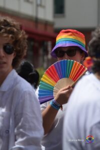 Una persona con cappellino e ventaglio arcobaleno