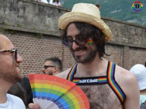 Una persona con cappello e ventaglio arcobaleno