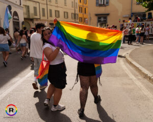 Una persona di spalle che tiene una bandiera arcobaleno